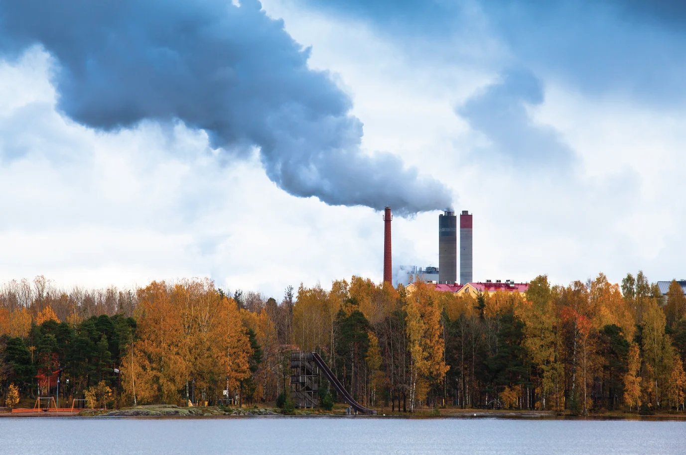 Air pollution by smoke coming out of three factory chimneys